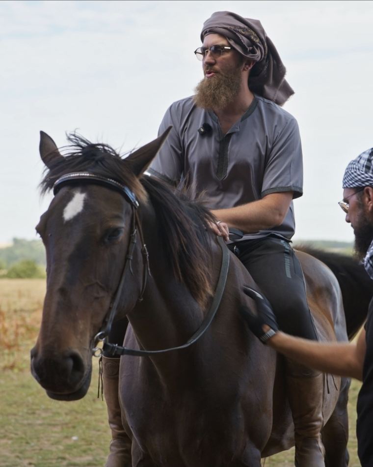 A rider in the saddle with an instructor leading the horse alongside